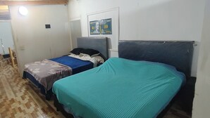 A small, narrow room with two beds, one with a blue blanket and the other with a teal blanket. There is a poster on the wall and a door leading to another room. - Starlink apartment, furnished, 4 to 6 persons, commercial area (Puerto Iguazú)