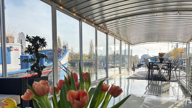 A covered outdoor area with a view of boats and water, a table with chairs, and a potted plant with flowers. - Entire bungalow for family or friends up to 15 people, terrace, unique! (Hlavní město Praha)