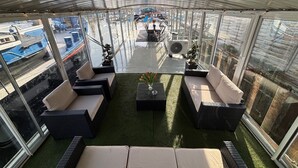 A covered outdoor seating area with wicker furniture and a central table, overlooking a busy street. - Entire bungalow for family or friends up to 15 people, terrace, unique! (Hlavní město Praha)
