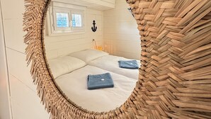 A circular mirror with a woven frame, reflecting a room with a bed, pillows, and a window. - Entire bungalow for family or friends up to 15 people, terrace, unique! (Hlavní město Praha)