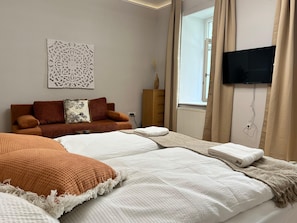 A modern hotel room with a large bed, a sofa, a TV, and a decorative wall piece. - Lovely Studio for 4 with Garden (Vienna)
