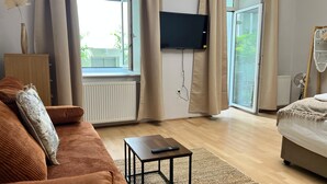 A modern living room with a sofa, a coffee table, and a bed. - Lovely Studio for 4 with Garden (Vienna)