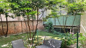 A courtyard with artificial grass, two metal-framed chairs, and a glass table. - Lovely Studio for 4 with Garden (Vienna)
