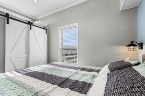A bedroom with a large bed, a window with blinds, a wall-mounted lamp, and a sliding door. - Waterfront Cottage Retreat in St. James City — Brand New 1BR/1BA with Private Dock & Boat Lift (Saint James City)