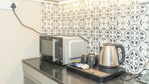 A kitchenette with a microwave, kettle, and coffee maker on a countertop. - Enjoyable 2-bedroom apartment with AC in vibrant Kolkata (Kolkata)