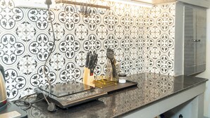 A kitchen with patterned backsplash tiles, a countertop with a coffee machine, and a knife block. - Enjoyable 2-bedroom apartment with AC in vibrant Kolkata (Kolkata)