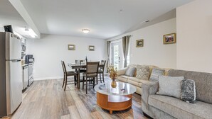 A modern living room with a grey sofa, a round coffee table, and a dining area with a table and chairs.