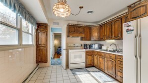 Une cuisine avec des meubles de rangement en bois, une cuisinière blanche et un luminaire suspendu.