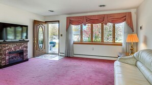 Un salon avec une cheminée, un canapé, un téléviseur et une fenêtre avec des rideaux.