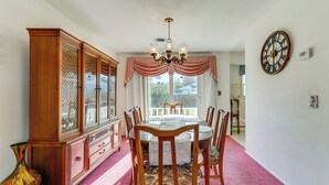 Une salle à manger avec un buffet en bois, un lustre et une table à manger entourée de chaises.