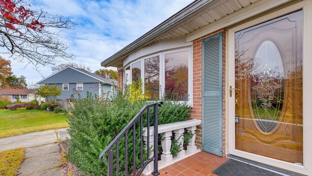 Une maison avec un porche à l’avant, une porte en bois et une fenêtre ornée de motifs décoratifs en verre.