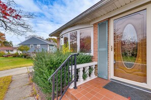 Ein Haus mit Veranda, einer Holztür und einem Fenster mit dekorativem Glasmuster.