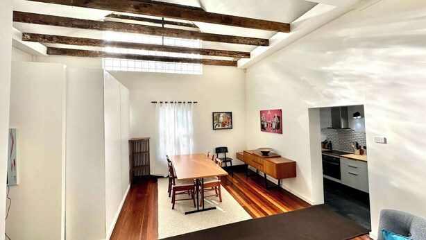 A spacious living area with a wooden dining table, a sofa, and a kitchen in the background. - MetaWiseBnB Spacious Apartment – 6km to CBD (Petersham)
