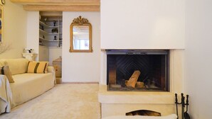 Sala de estar com lareira, sofá e espelho.