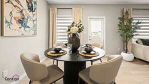 Un coin repas avec une table ronde, quatre chaises, un vase de fleurs et un tableau accroché au mur.