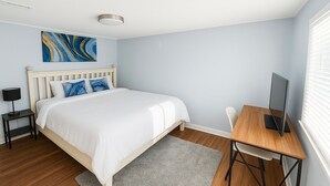 Un dormitorio con cama, escritorio, televisor y un cuadro en la pared.