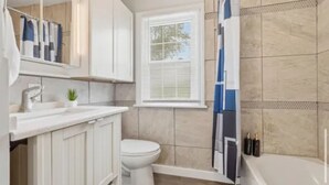 Un baño moderno con inodoro blanco, lavabo con espejo y bañera.