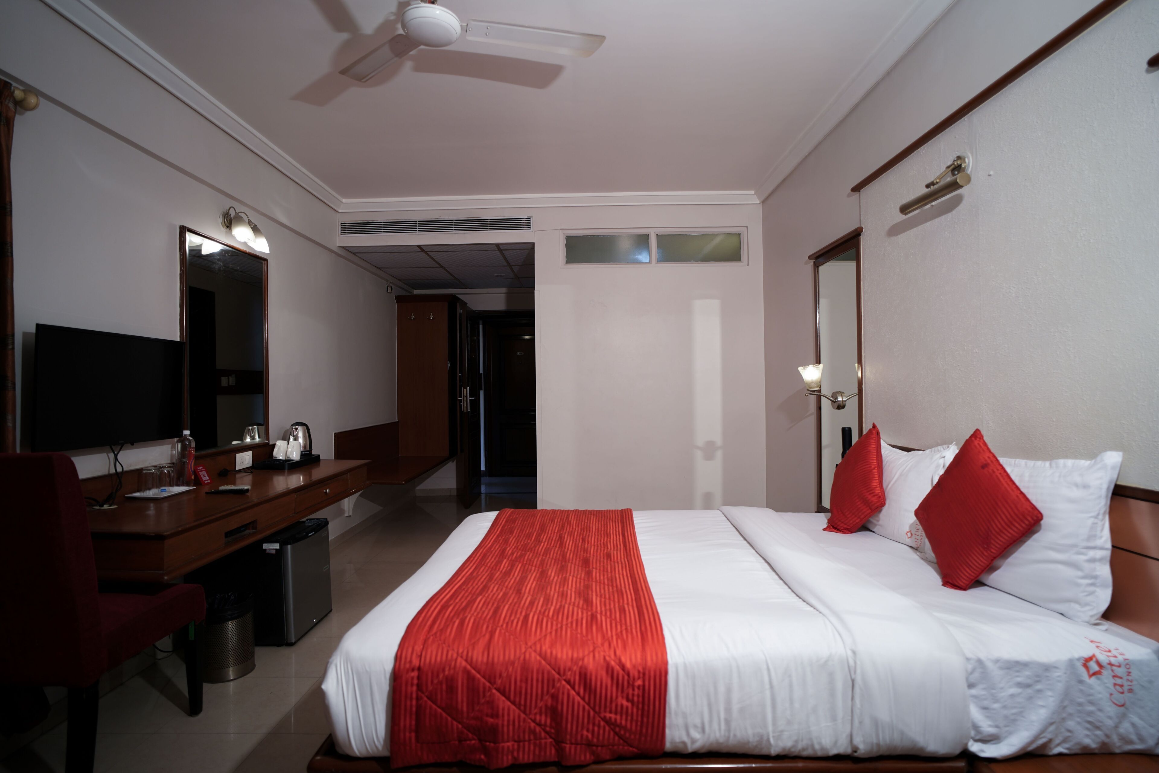 A hotel room with a bed, a desk, a television, and a mirror.