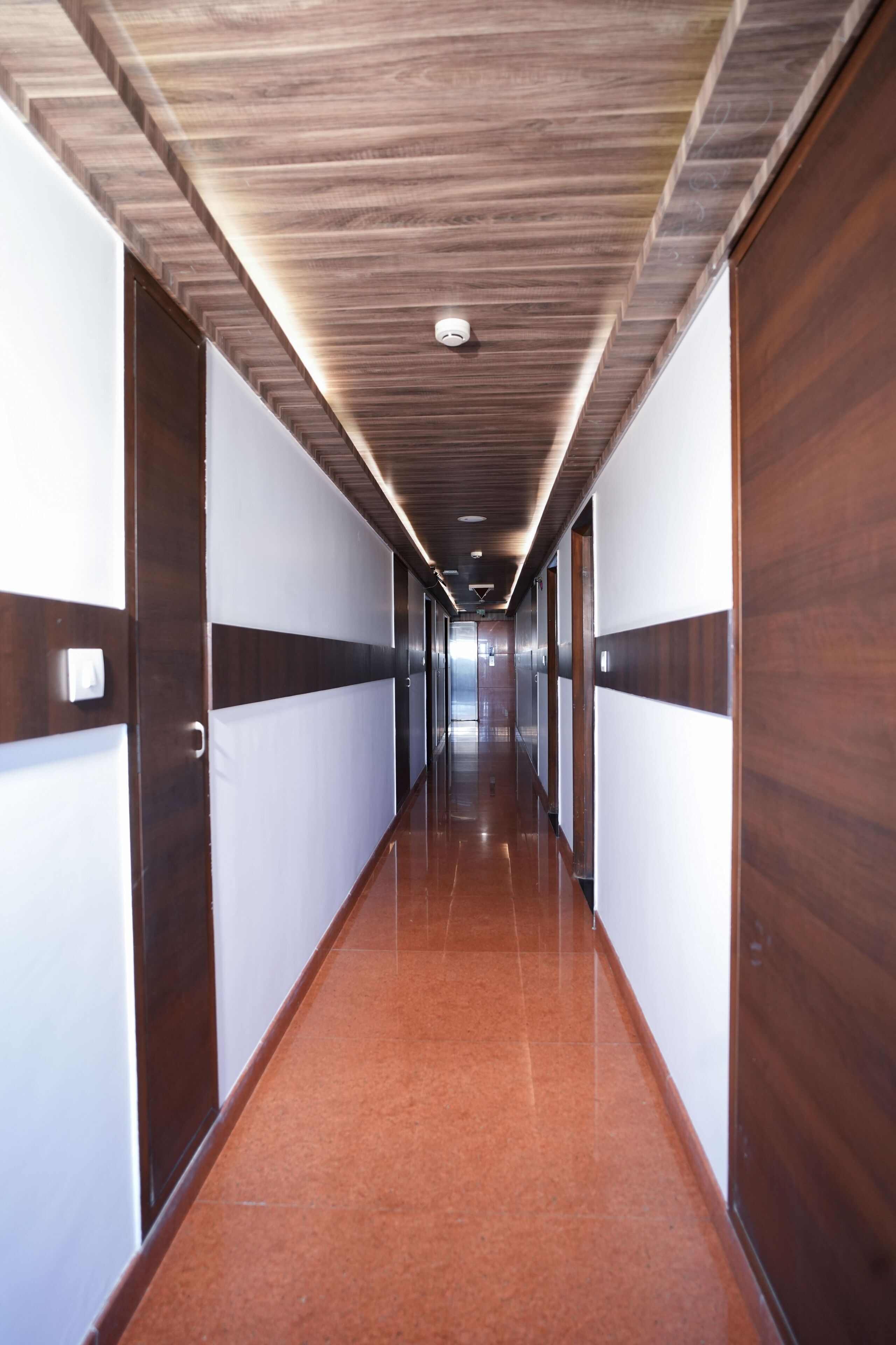 A long, narrow hallway with wooden paneling on the walls and a polished tile floor.