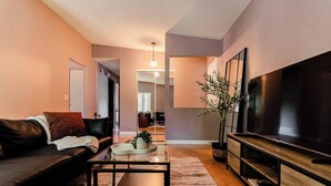 A modern living room with a sofa, coffee table, and a large flat-screen TV. - Spacious 3BR Home with Fast Wi-Fi and Free Parking (Winnipeg)