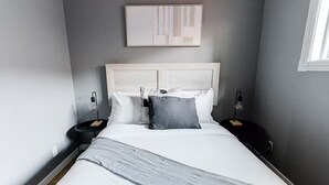 A modern bedroom with a large bed, two bedside tables, a wall-mounted artwork, and a window. - Spacious 3BR Home with Fast Wi-Fi and Free Parking (Winnipeg)