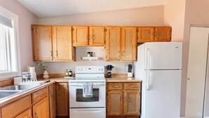 A kitchen with wooden cabinets, a white stove, a sink, and a refrigerator. - Spacious 3BR Home with Fast Wi-Fi and Free Parking (Winnipeg)