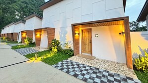A row of modern hotel rooms with wooden accents, a checkered entrance, and a mountain backdrop. - Tambuna Retreat & Events (Ipoh)