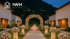 A wedding arch with floral arrangements, a table with chairs, and a building facade with 'IWH Suites' branding. - Tambuna Retreat & Events (Ipoh)