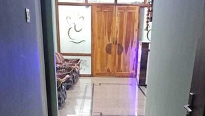 A hallway with a polished floor leading to a room with a wooden door and a decorative wall. - Pratimalaya Inn Guest House (Varanasi)