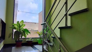 A staircase with metal railings, potted plants, and a view of the outside. - Pratimalaya Inn Guest House (Varanasi)