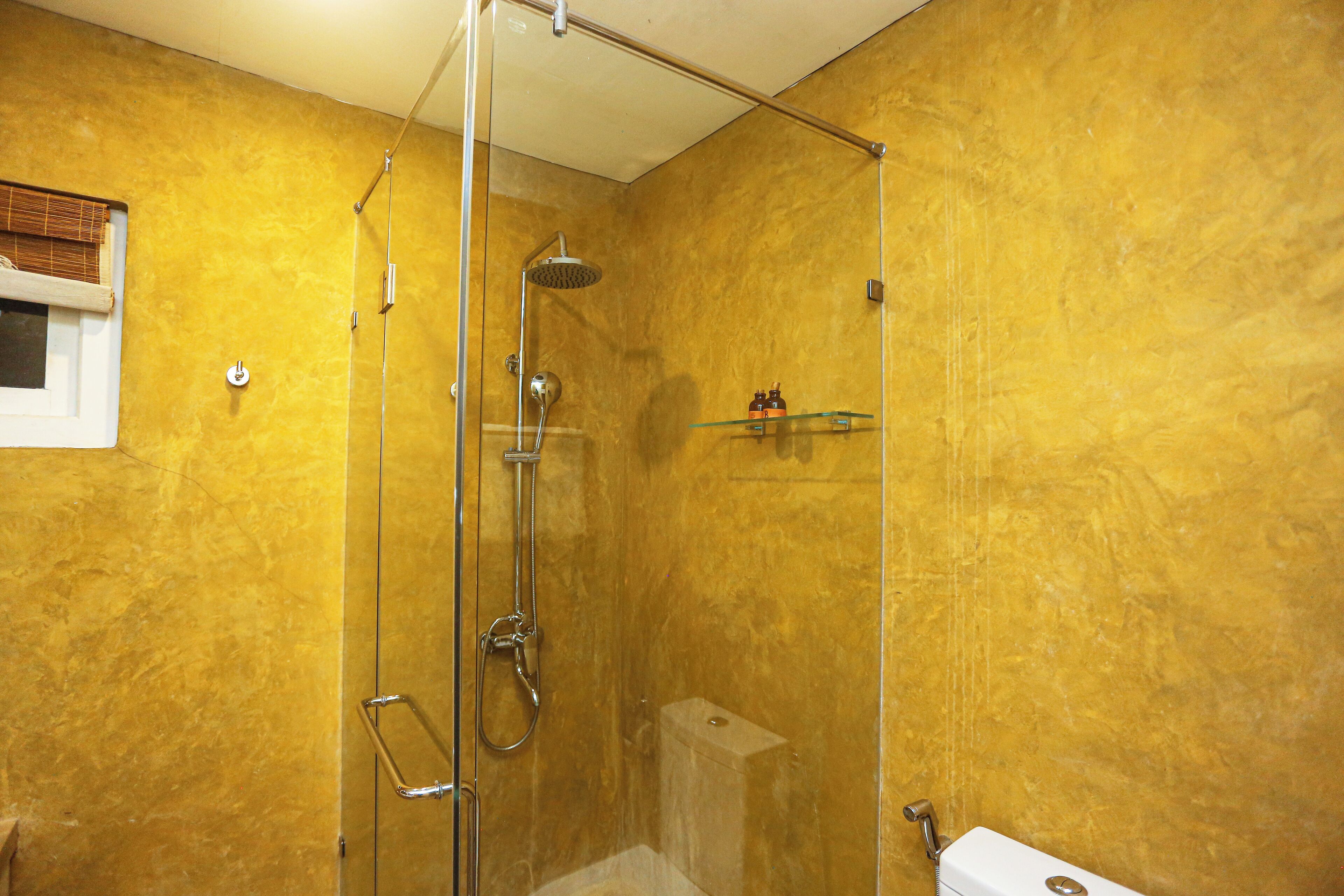 A glass-enclosed shower with a handheld showerhead and a wall-mounted faucet.