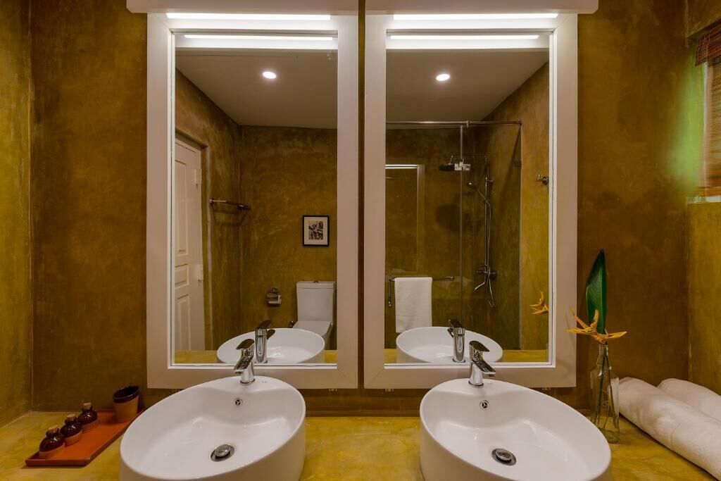 A bathroom with two sinks, a shower, and a large mirror.