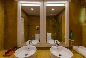 A bathroom with two sinks, a shower, and a large mirror.