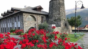 A stone building with a bell tower and a garden of red flowers. - hotel palas (Bruzolo)