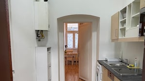 Una cucina angusta con pavimento piastrellato, una lavatrice e una finestra che dà su un'area pranzo.