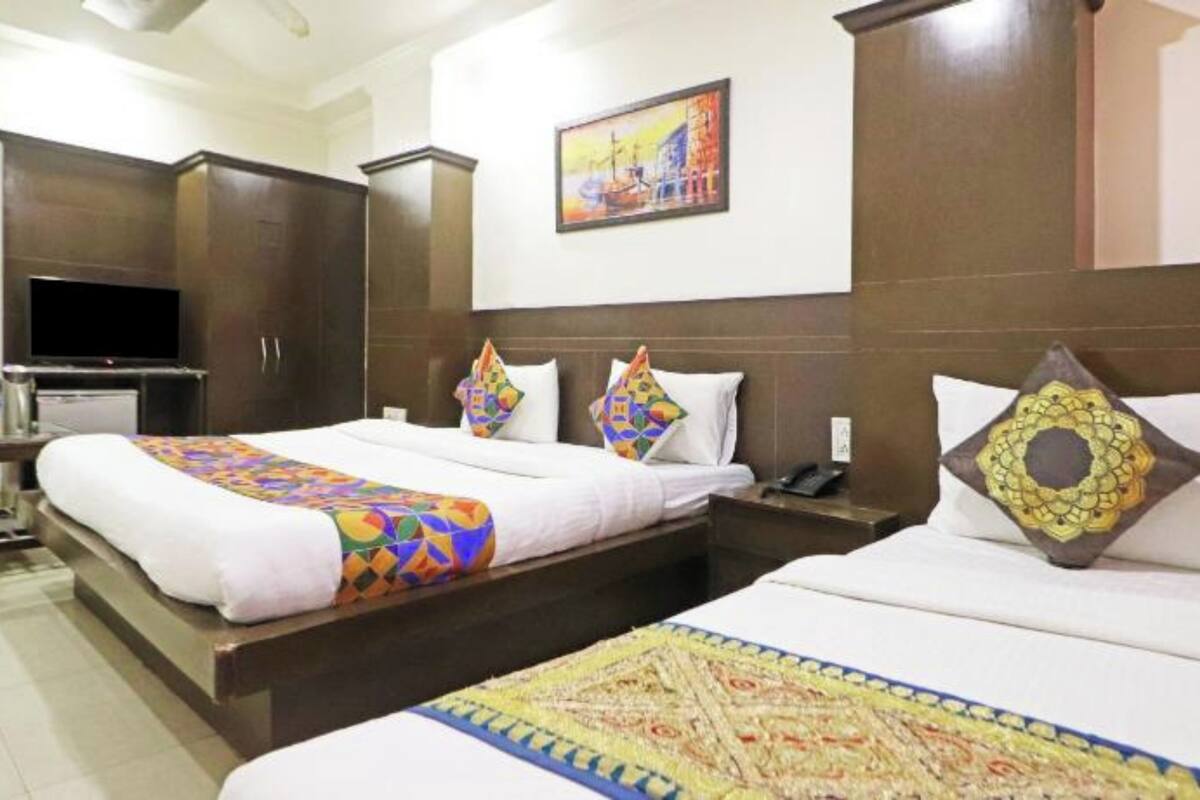 Una habitación de hotel con una cama grande, un televisor y un cuadro en la pared.