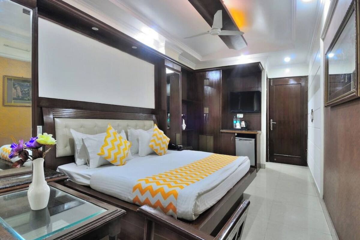 Habitación de hotel con cama, mesita de noche y una pequeña kitchenette.