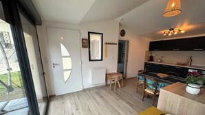 Une cuisine moderne avec des meubles de couleur noire, une table à manger en bois et un mur d’accent jaune.