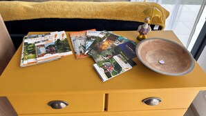 Une table jaune sur laquelle sont posées des brochures de voyage, un bol en céramique et une figurine de canard.