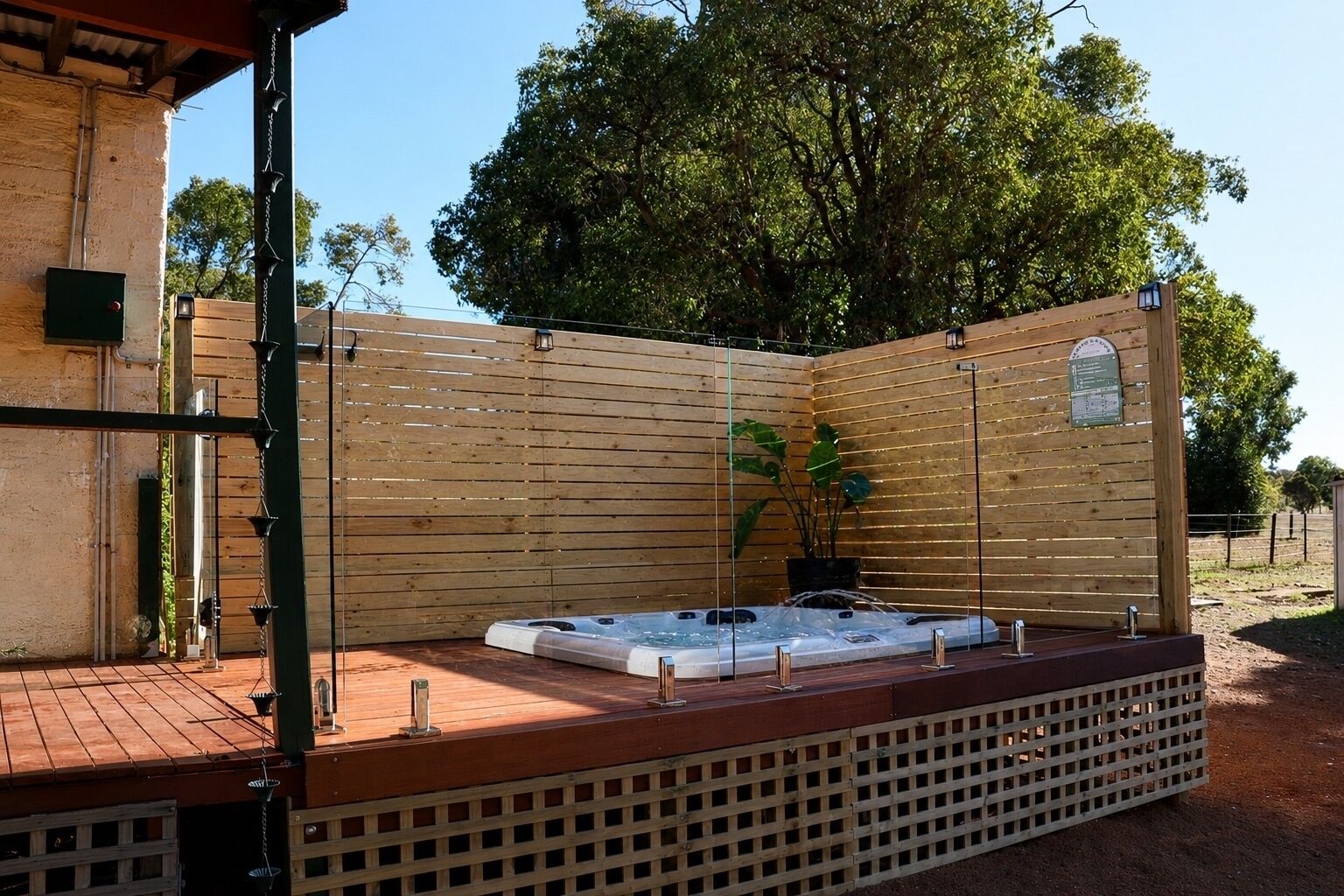 A hot tub in a covered outdoor area with wooden fencing and a wooden deck.