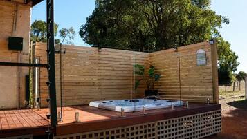 A hot tub in a covered outdoor area with wooden fencing and a wooden deck.