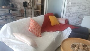 Et moderne soveværelse med en stor seng, et lille rundt bord med dekorative genstande, et garderobeskab og et tekøkken.
