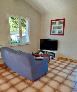 Olohuone, jossa on sohva, televisio ja laattalattia.