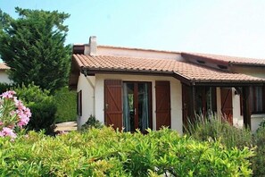 A house with a tiled roof, a chimney, and a garden with various plants and flowers. - Holiday house close to the ocean G0238 (Lacanau Ocean)