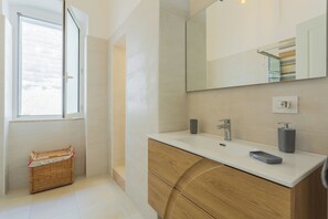 Un baño moderno con un espejo grande, un lavabo y un mueble de tocador de madera.