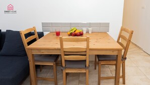 A dining area with a wooden table, four chairs, a bowl of fruit, and two cups. - Quiet Oasis in the Center (Netanya)