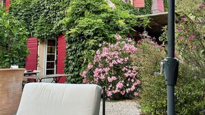 A patio area with a white cushioned chair, a table, and a potted plant. - Charming house with direct view of Sainte Victoire and Picasso castle. (Vauvenargues)