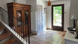 A staircase leading to a landing with a wooden cabinet, a door, and a view of greenery outside. - Charming house with direct view of Sainte Victoire and Picasso castle. (Vauvenargues)