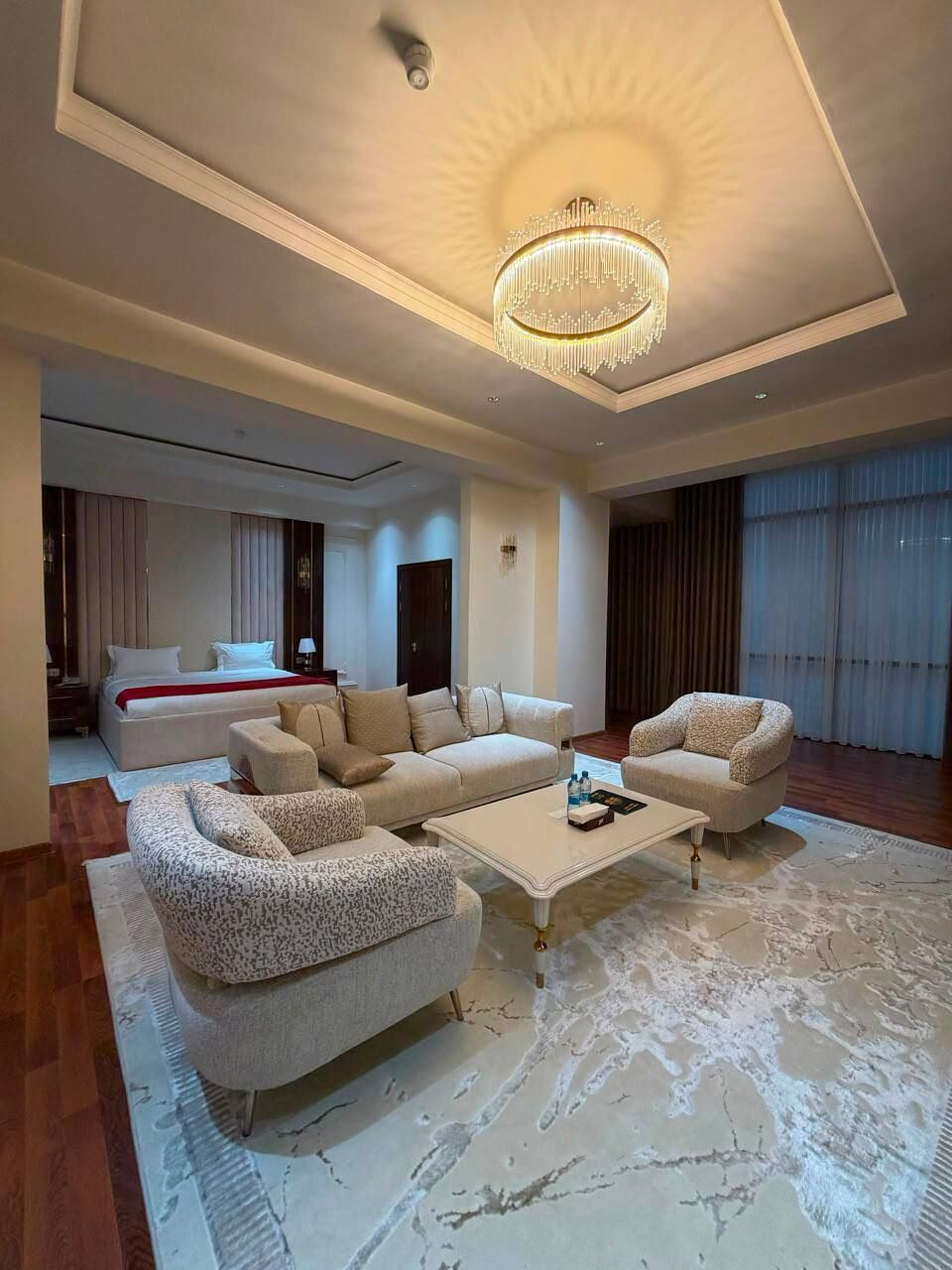 A spacious living area with a modern chandelier, a large sofa set, and a coffee table.