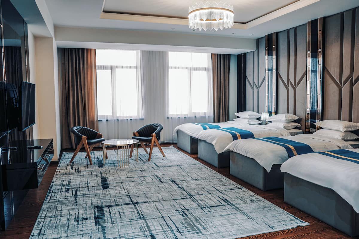 Ein Hotelzimmer mit einem großen Bett, einem Fernseher, einer Sitzecke mit Stühlen und einer Kristallleuchtreiter.